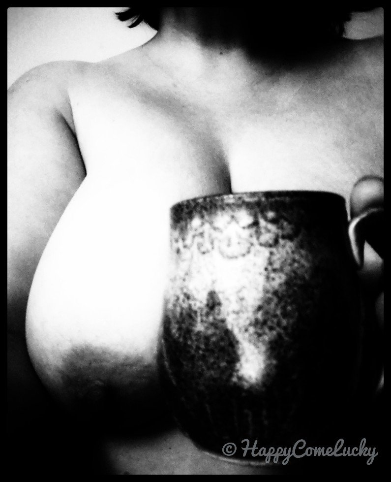 Black and white image of a woman holding a mug. One breast visible.