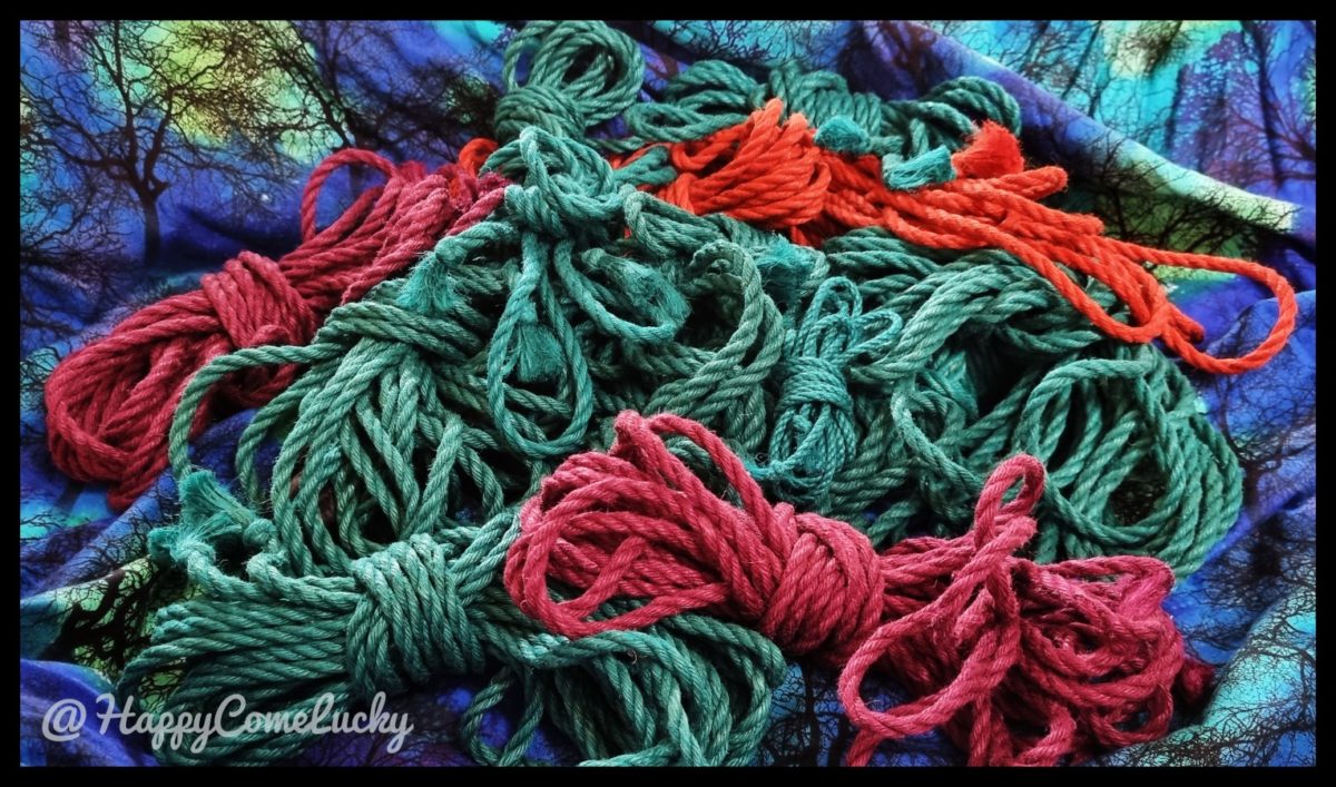 Bundles of rope on a beautiful woodland cloth. The ropes are teal-green, orange and burgundy.